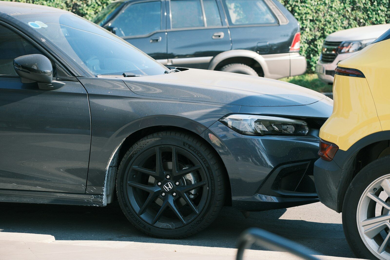 A dark gray car is parked in the daylight.